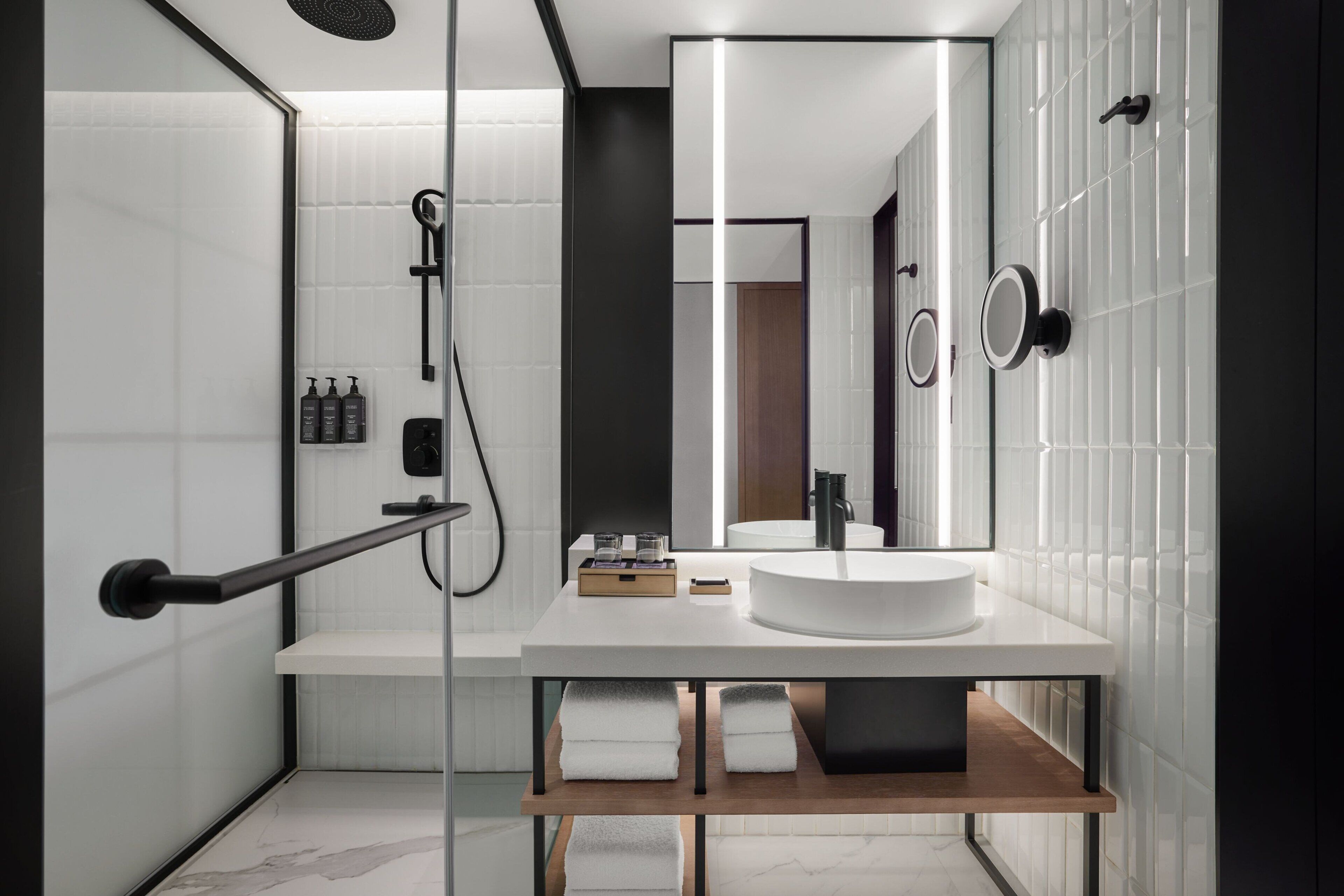 Un baño moderno con cabina de ducha de vidrio, un lavabo blanco y un espejo grande.