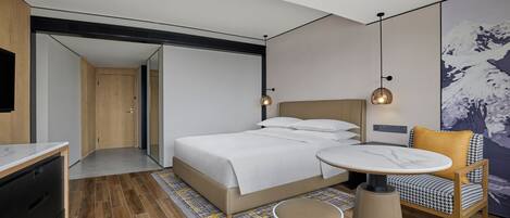 Una habitación de hotel moderna con una cama, una mesa redonda, una silla y un cuadro en la pared.