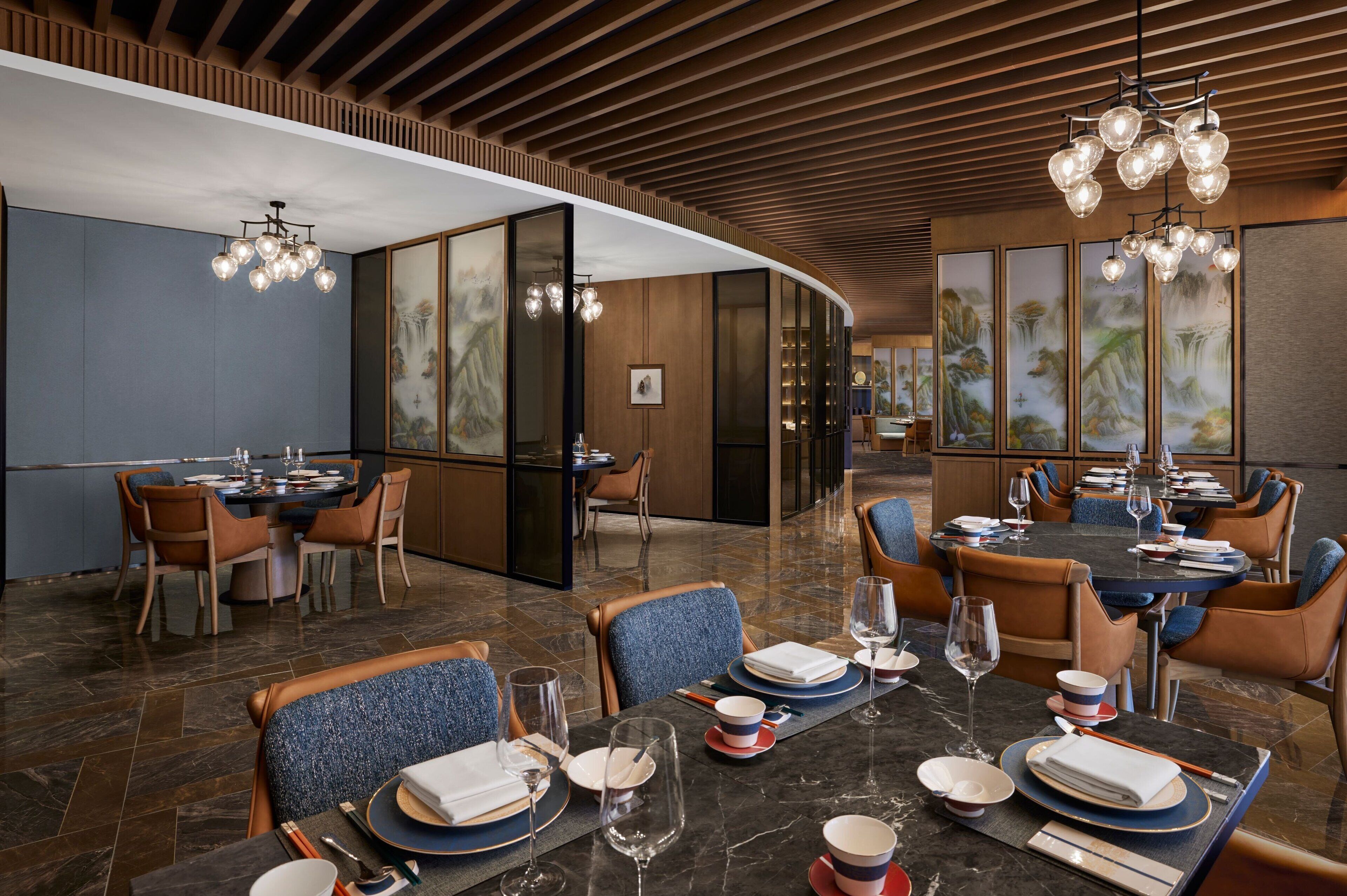 A modern dining area with wooden paneling, a curved ceiling, and traditional artwork on the walls.
