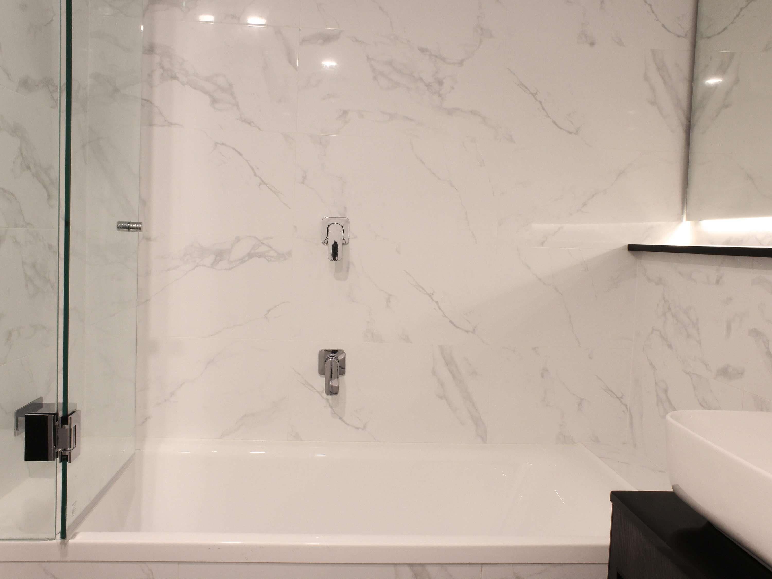 Une salle de bain moderne avec une douche à parois de verre, une baignoire blanche et un plan de toilette noir.