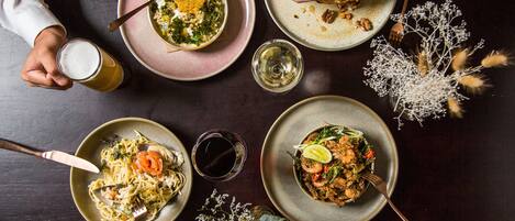 A dining table with multiple plates of food, utensils, and glasses.