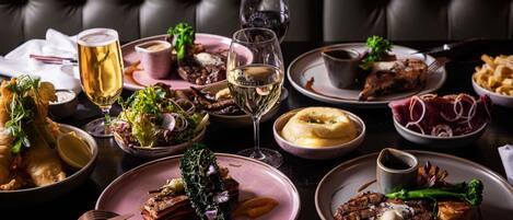 A dining table with various dishes, a glass of white wine, and a glass of beer.