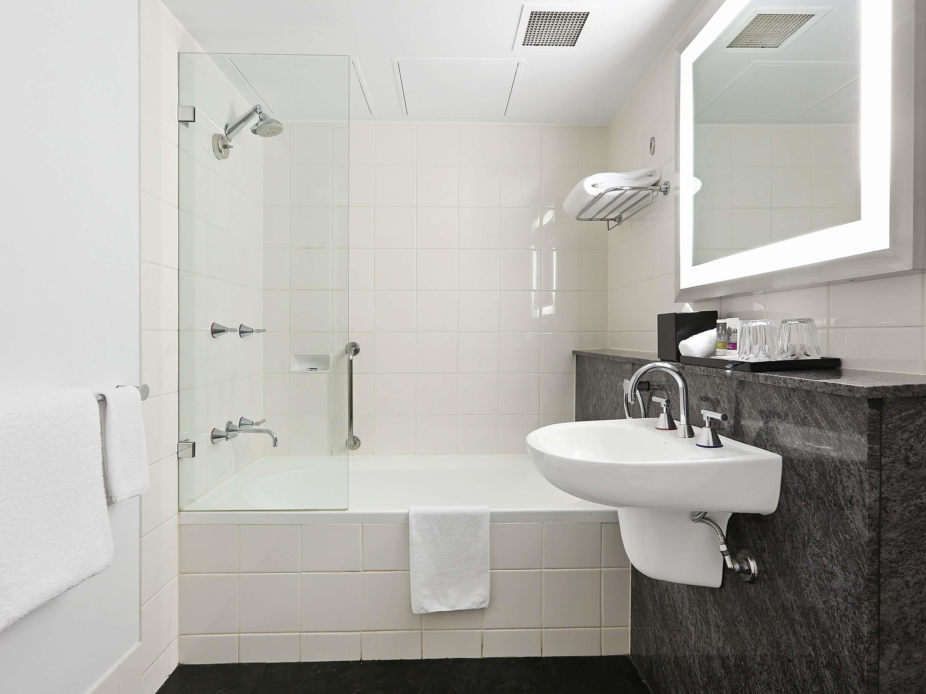 A modern bathroom with a glass-enclosed shower, a white sink, and a marble countertop.