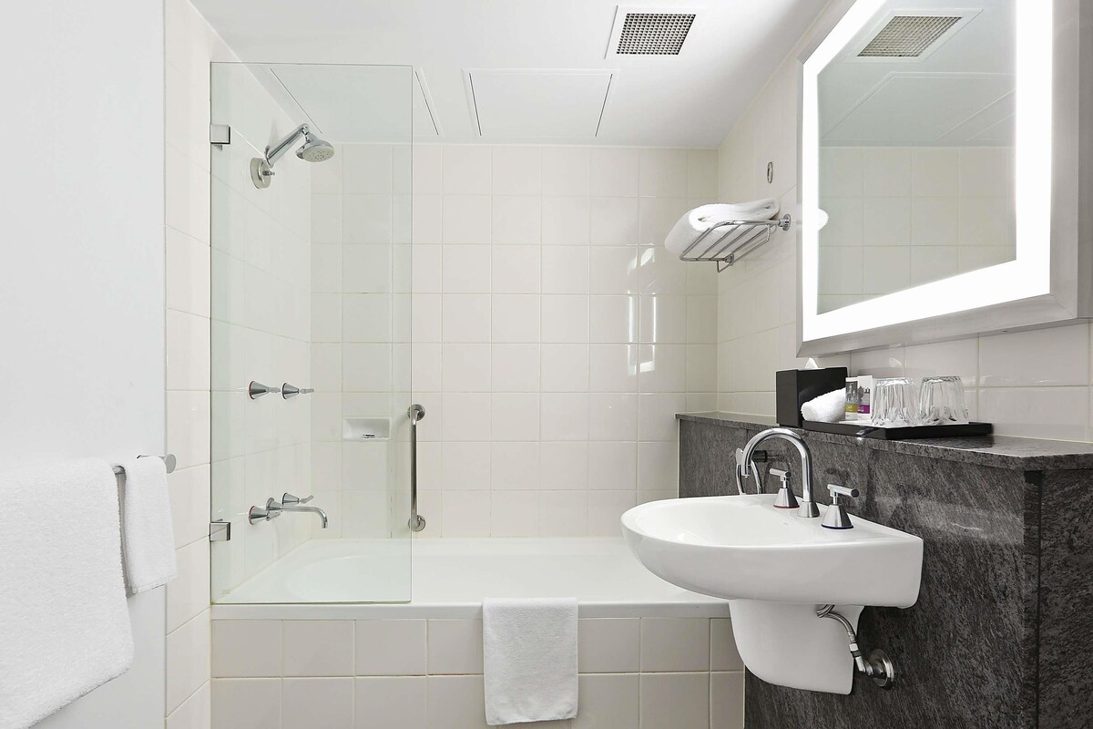 A modern bathroom with a glass-enclosed shower, a white sink, and a marble countertop.