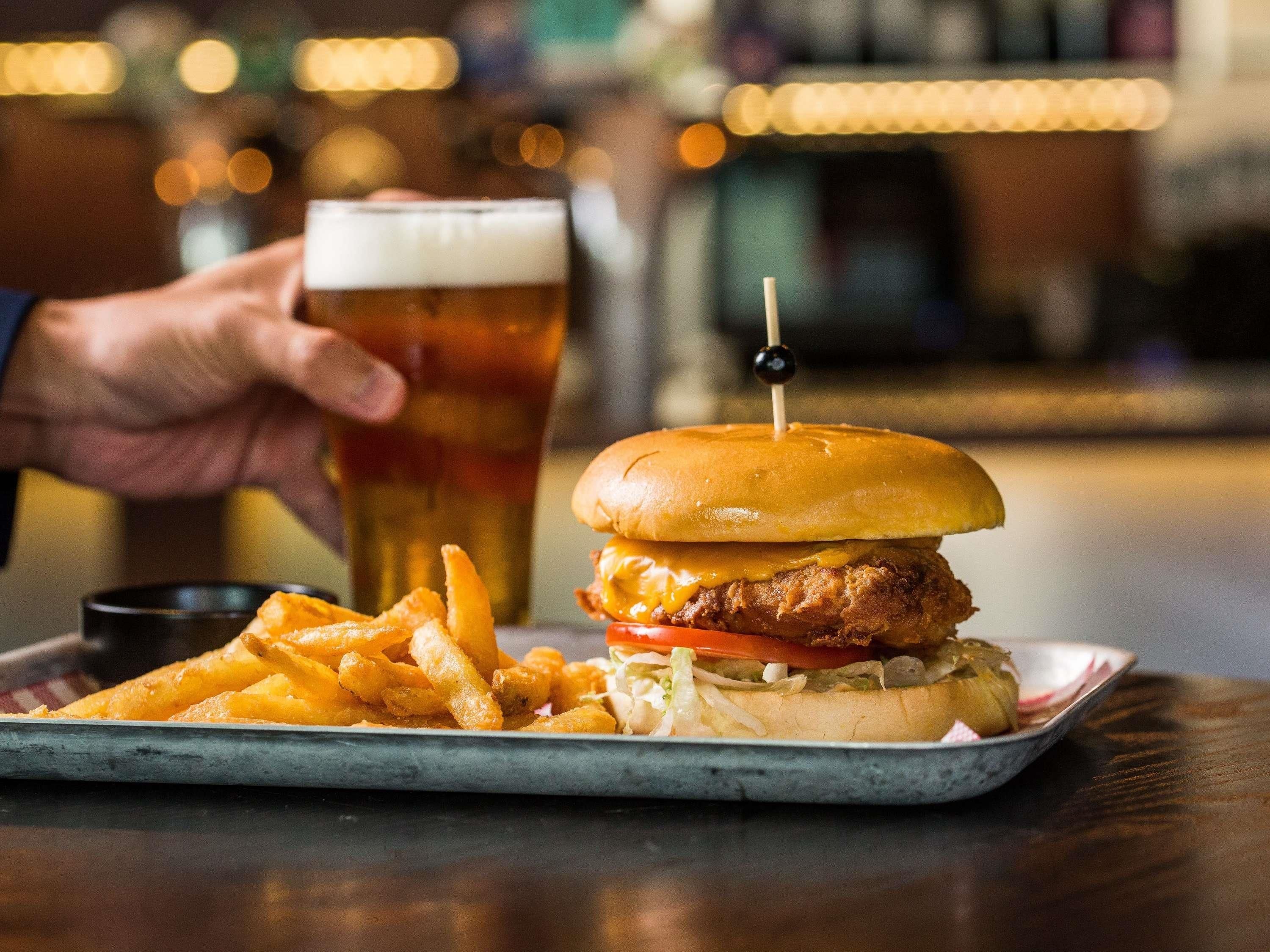 A meal with a burger, fries, and a glass of beer on a tray.