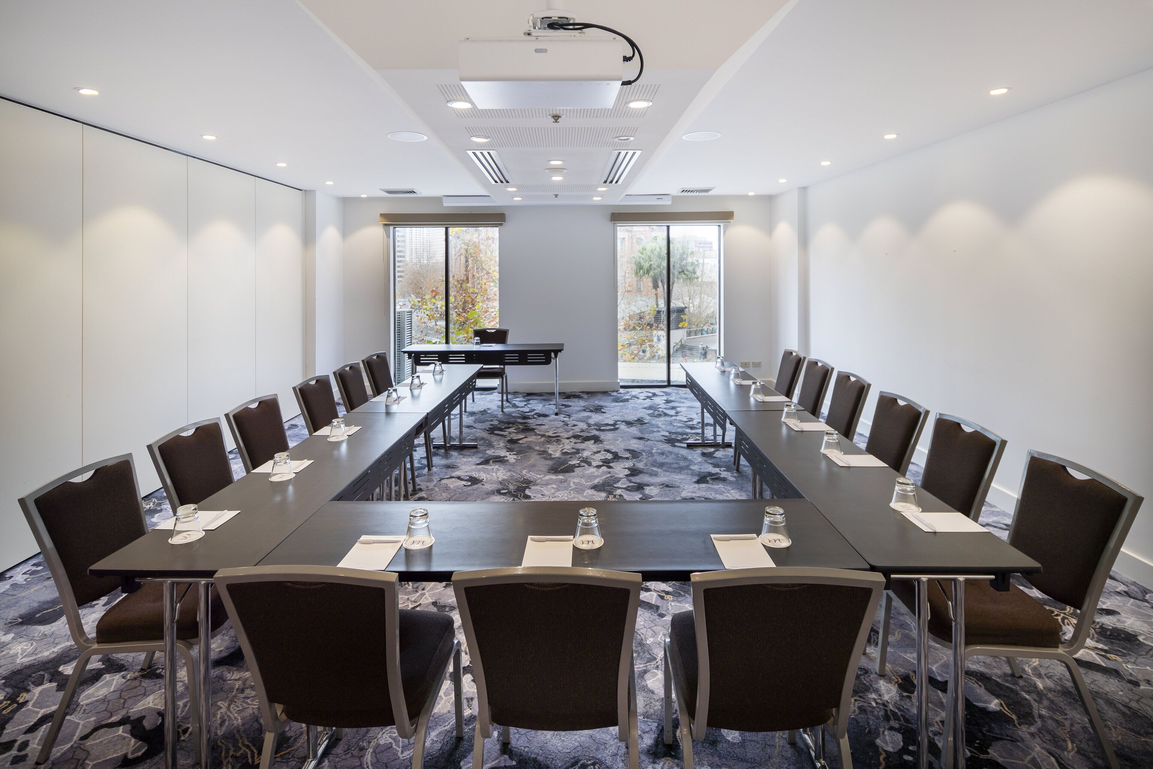 Une salle de conférence équipée d’une longue table, de chaises et d’un projecteur.