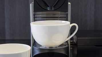 Eine Kaffeemaschine mit Tasse und Löffel auf einer Arbeitsplatte.
