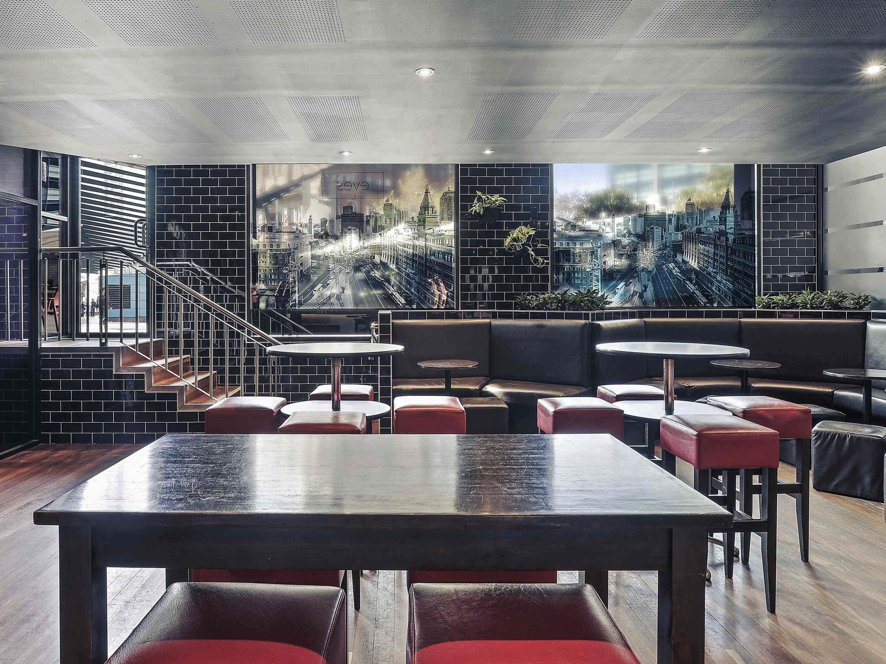 A modern restaurant with a cityscape view, black brick walls, and leather seating.