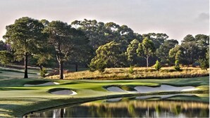A golf course with sand bunkers, a water hazard, and dense trees in the background. - Mercure Sydney (Chippendale)