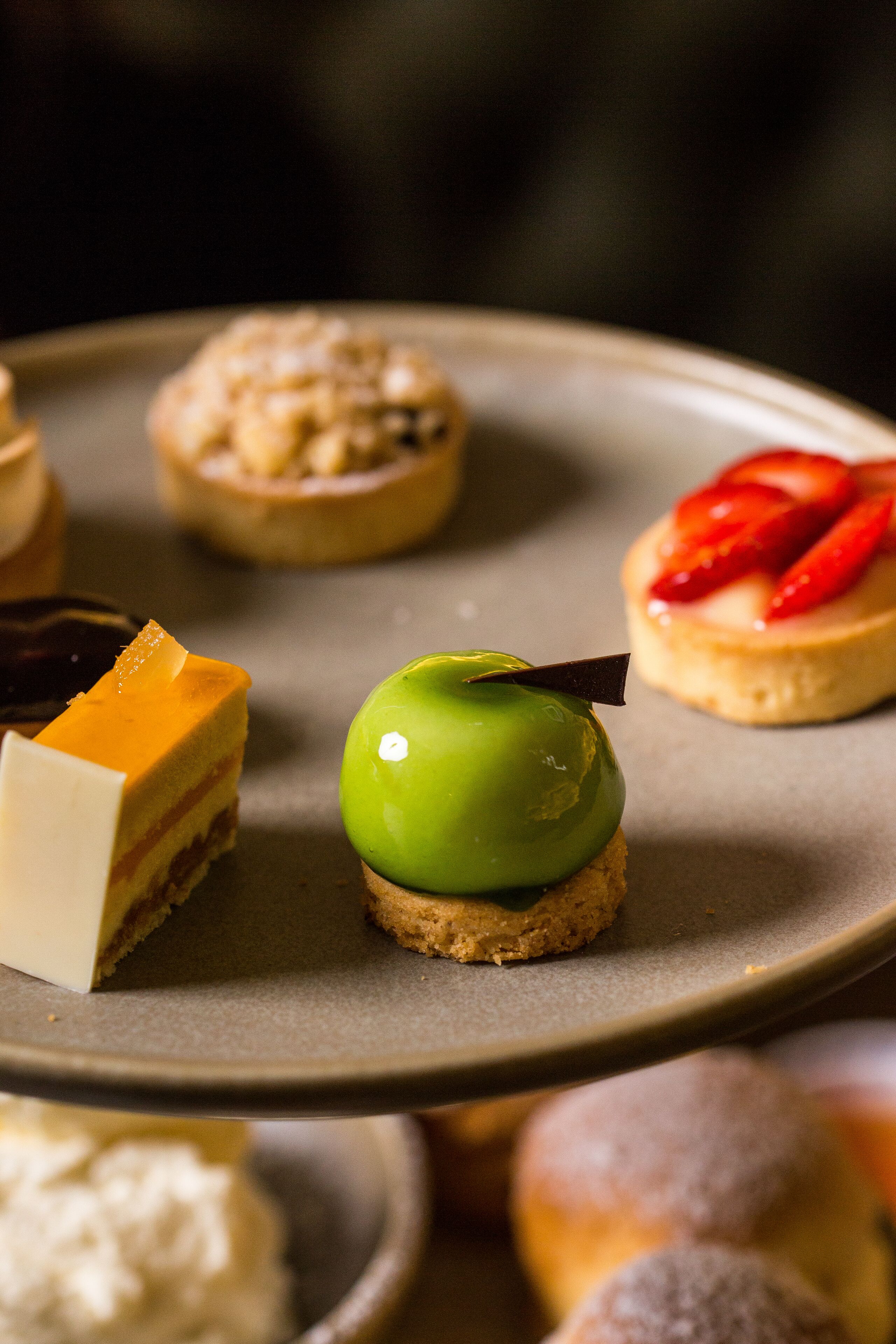 A plate with various desserts including a green apple tart and a strawberry tart.