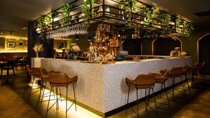 A bar area with a speckled countertop, bar stools, and a variety of bottles and glasses. - Mercure Sydney (Chippendale)
