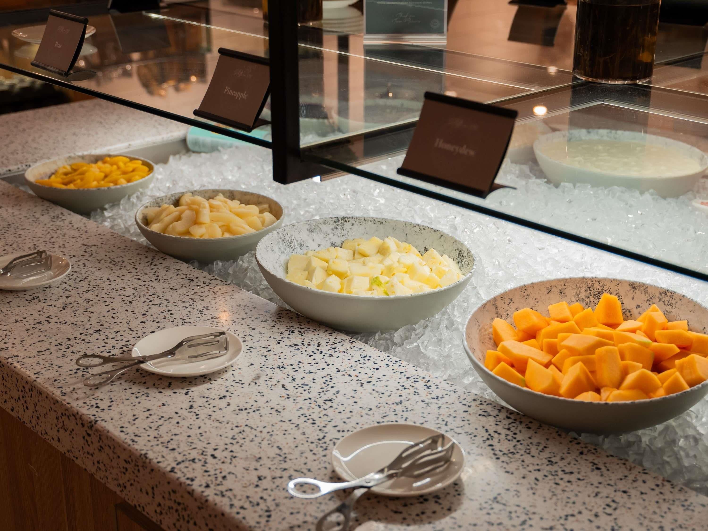 A buffet with various food items displayed in bowls on a speckled countertop.