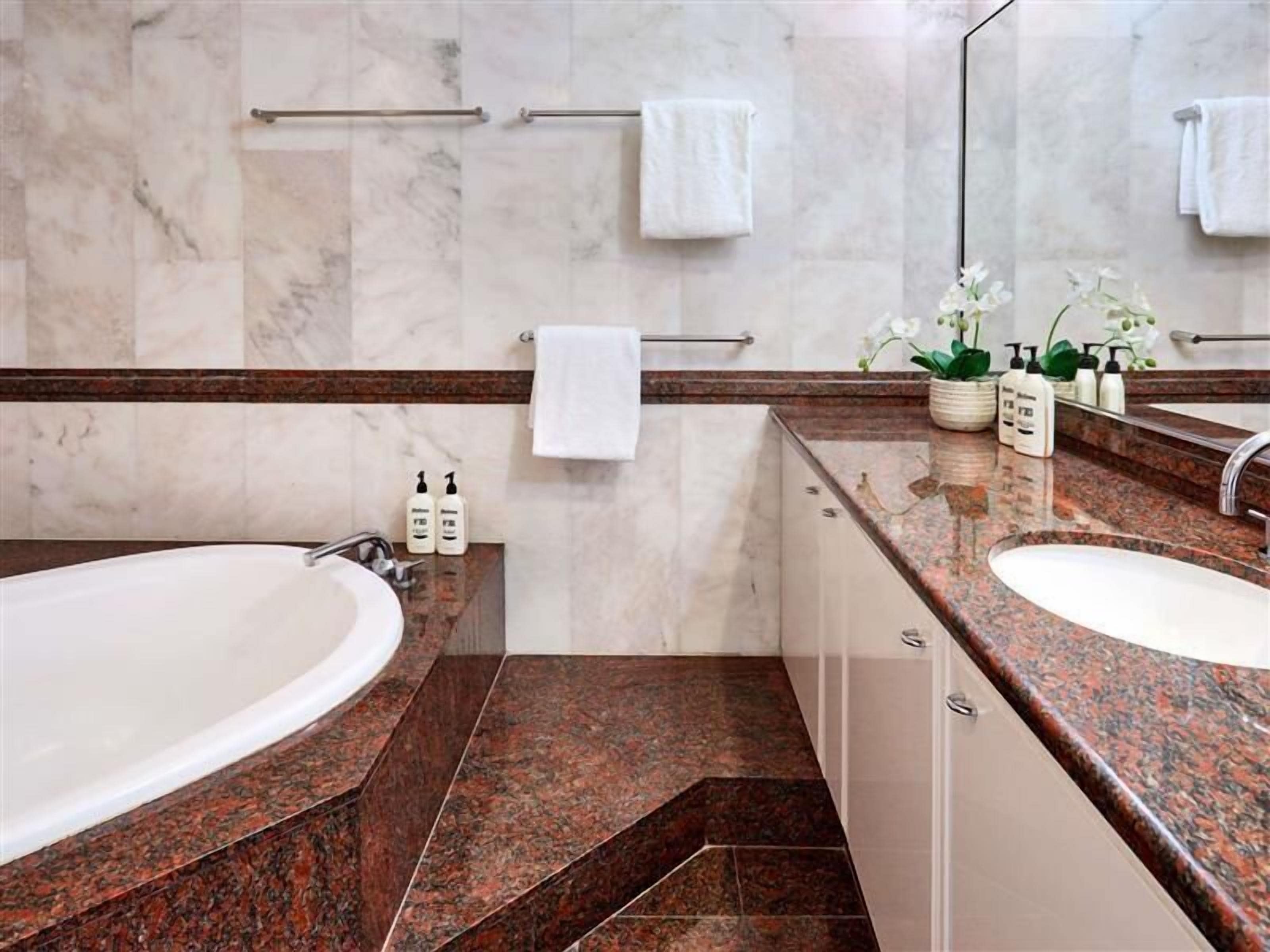 A modern bathroom with two sinks, marble walls, and a large mirror.