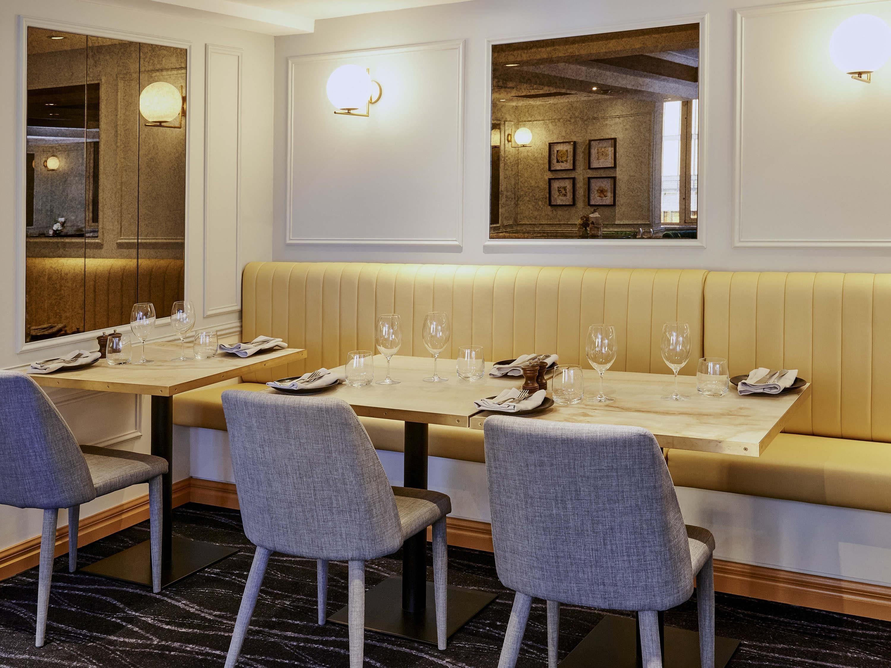 A dining area with a long table, cushioned bench seating, and modern decor.