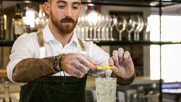 Un barman prépare un cocktail en ajoutant une tranche de citron vert.