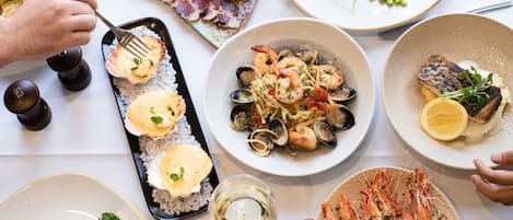 Variedad de platos en una mesa, incluyendo mariscos, pasta y un plato con una rodaja de limón.