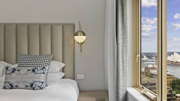 Habitación de hotel con una cama grande, una lámpara de pared y una ventana con vistas a un paisaje urbano y un famoso teatro de ópera.