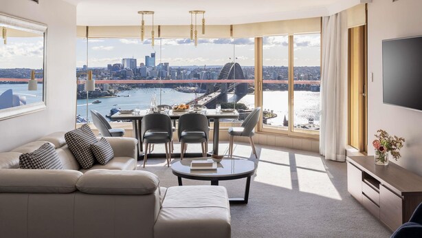 A modern living room with a city view, a dining area, and a TV.