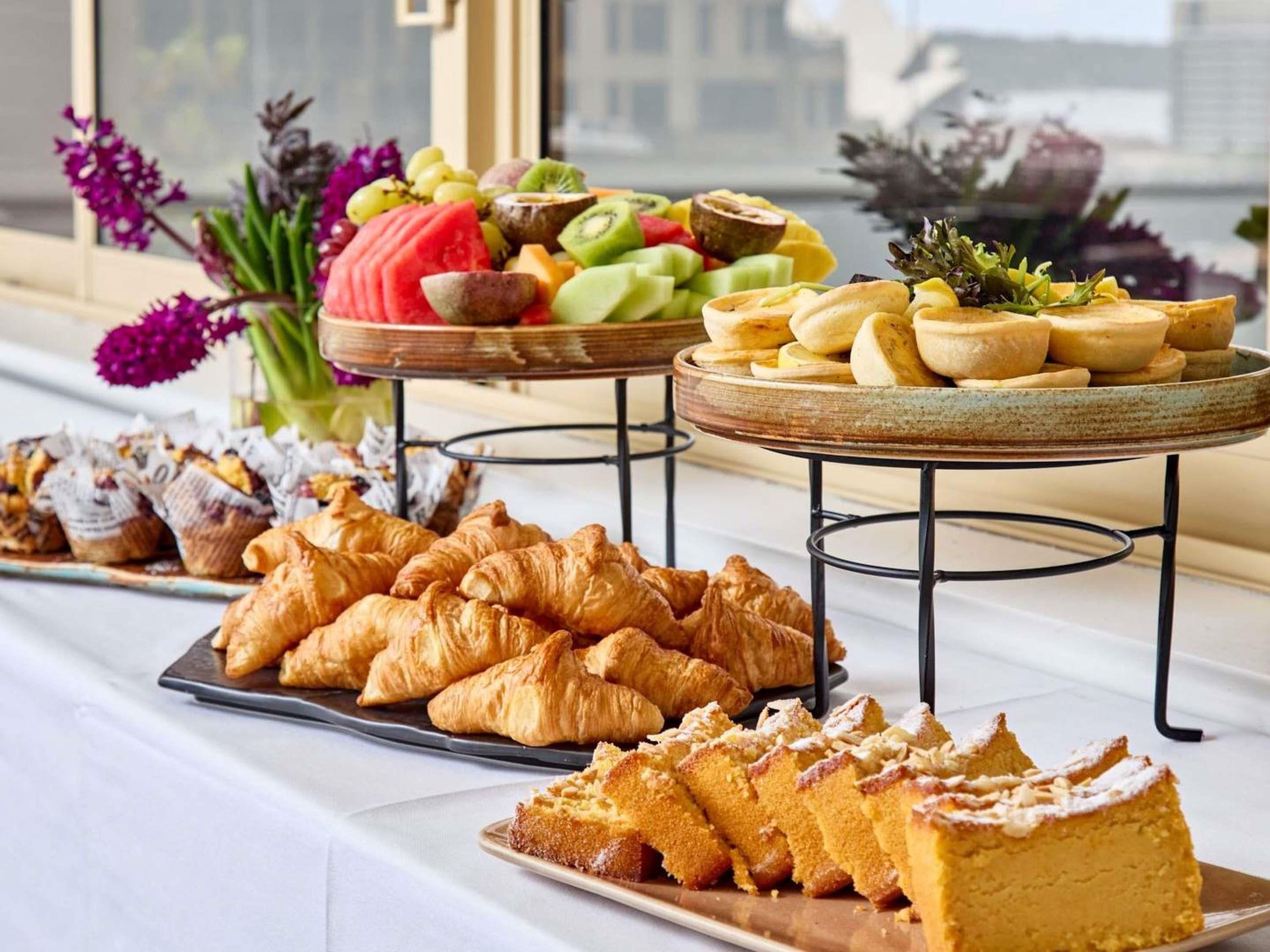 A buffet with pastries, fruits, and a cake.