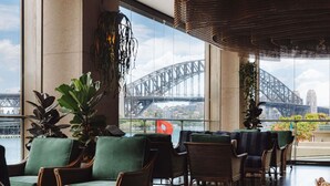 A spacious indoor area with wicker furniture and large windows offering a view of a bridge and cityscape.