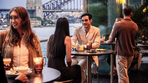 A group of people dining at a table with a view of the Sydney Harbour Bridge. - Pullman Quay Grand Sydney Harbour (Sydney)