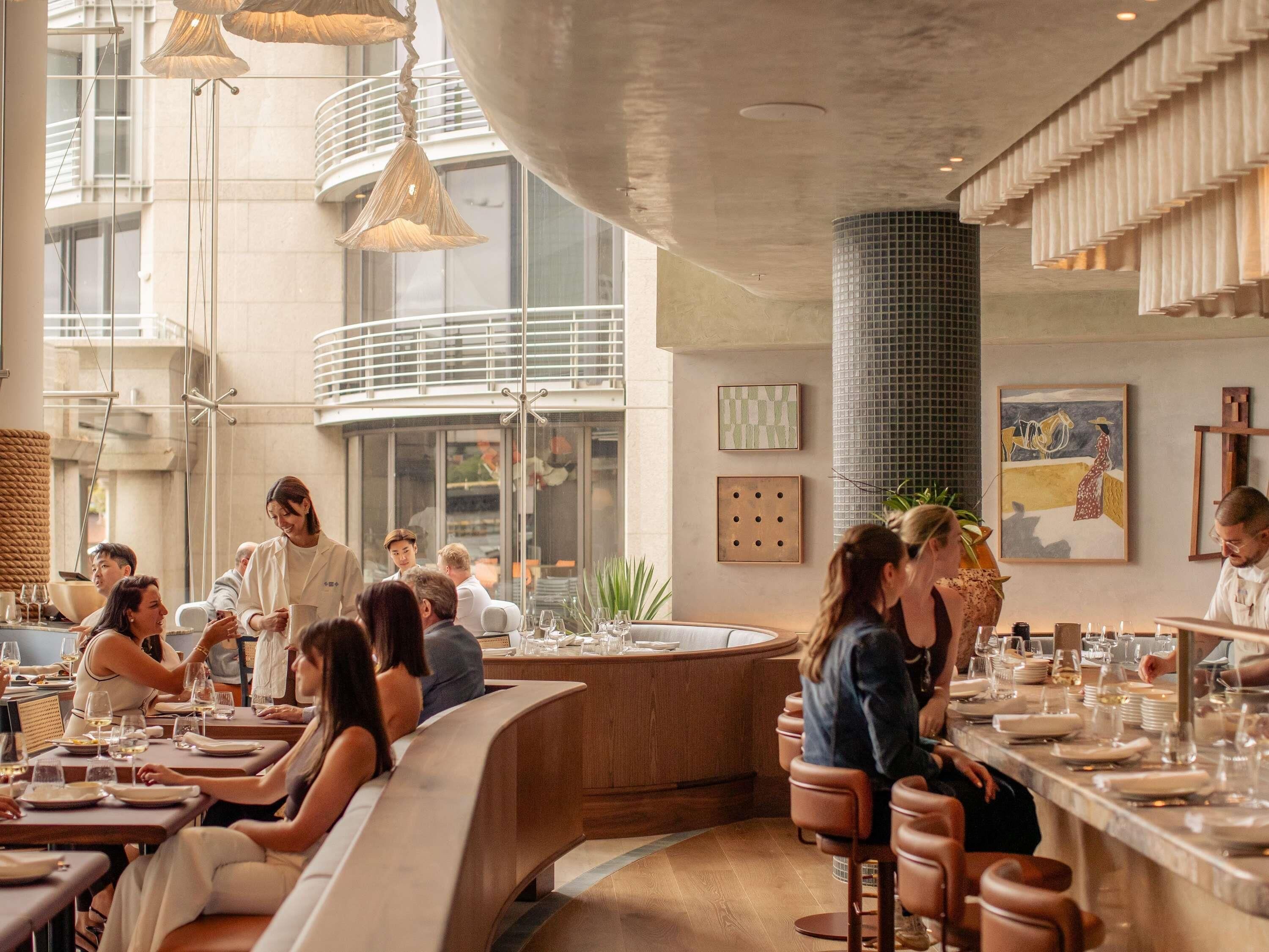 Un restaurante moderno con una barra curva y zonas de estar.