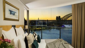 A hotel room with a bed, a view of a bridge, and a cityscape.