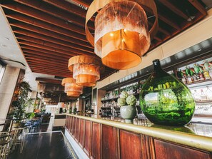 A bar area with wooden ceiling beams, hanging lamps, and a large green vase on the counter. - Pullman Quay Grand Sydney Harbour (Sydney)