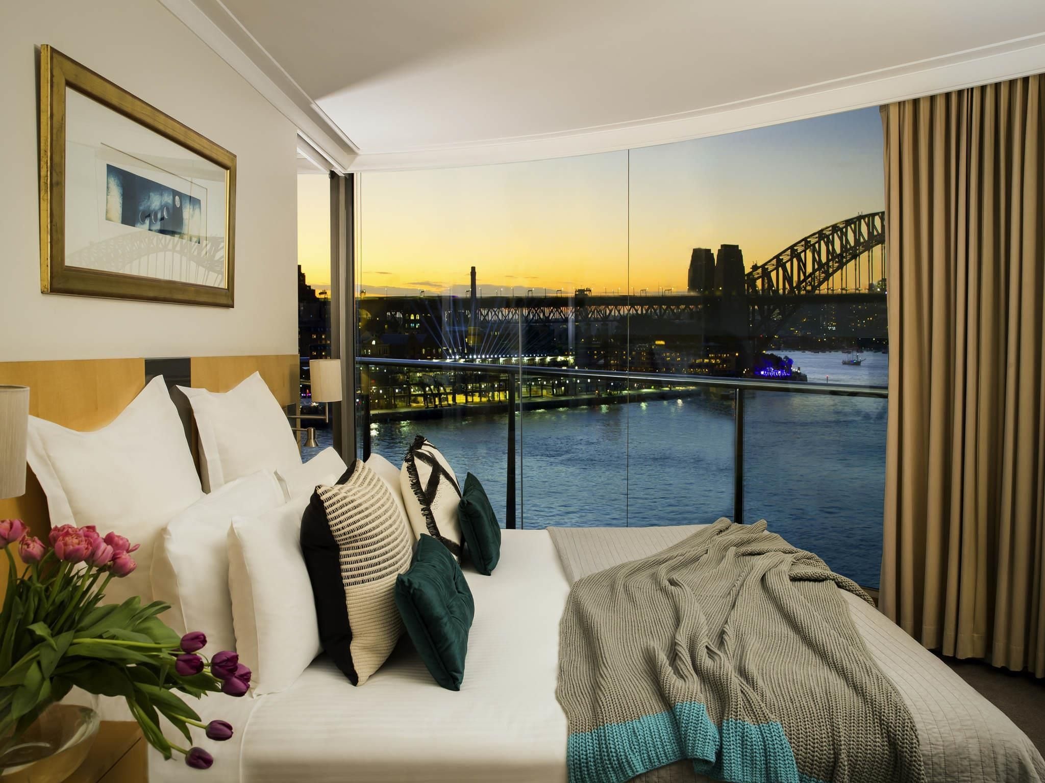 A hotel room with a large window offering a view of a bridge and city skyline.
