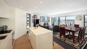 Un apartamento moderno con cocina, comedor y sala de estar. Cuenta con una isla grande, una mesa de comedor con sillas y un sofá.