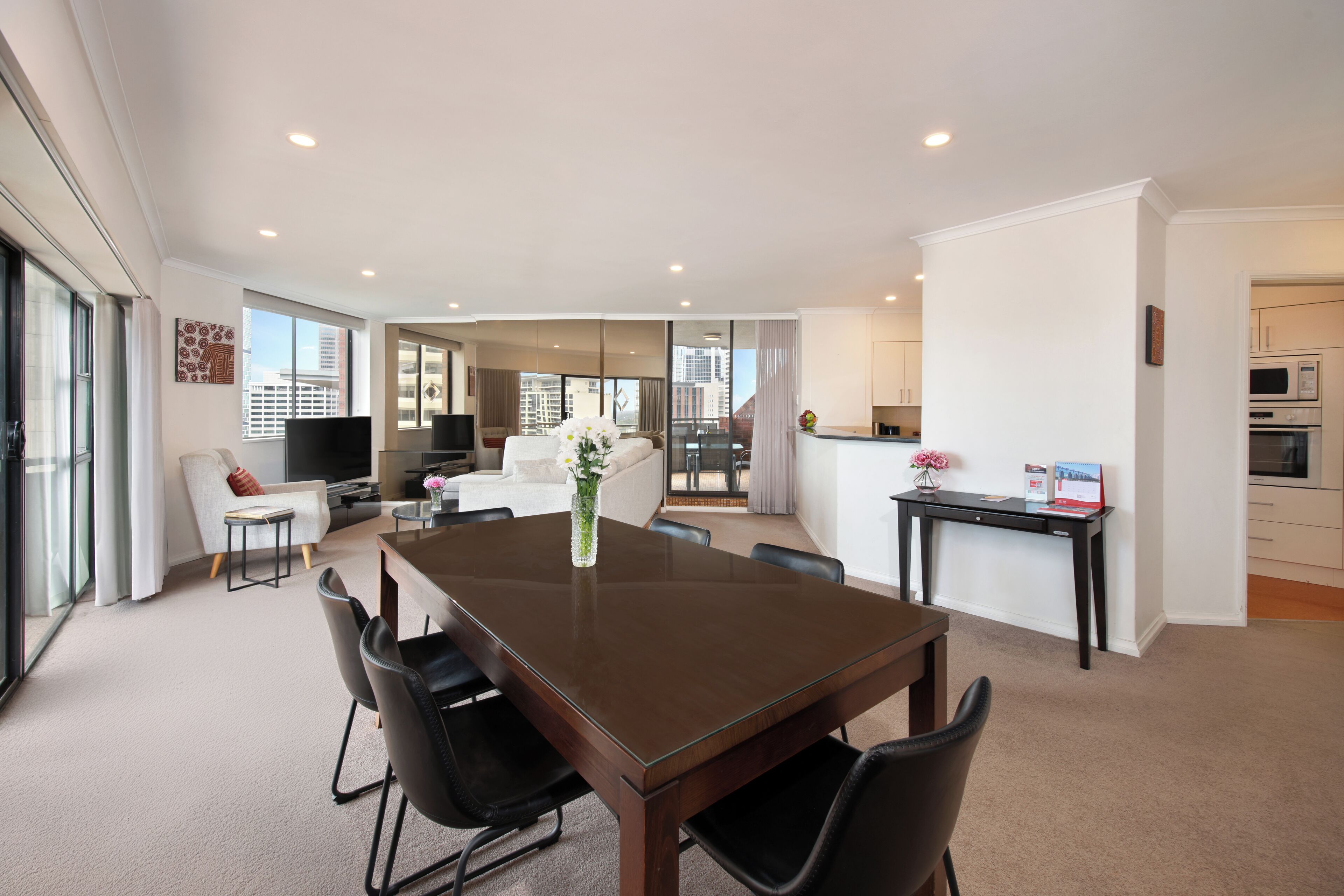 A modern living room with a dining table, black chairs, a sofa, and a TV.