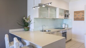 Une cuisine moderne dotée d’un îlot central, de meubles blancs, d’un four à micro-ondes, d’un évier et d’un four.