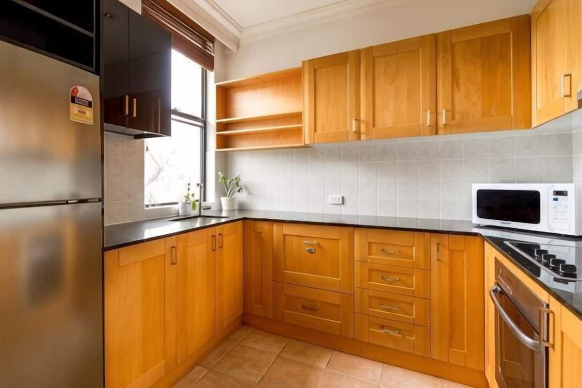 Una cocina con armarios de madera, un refrigerador de acero inoxidable, un microondas y una estufa.