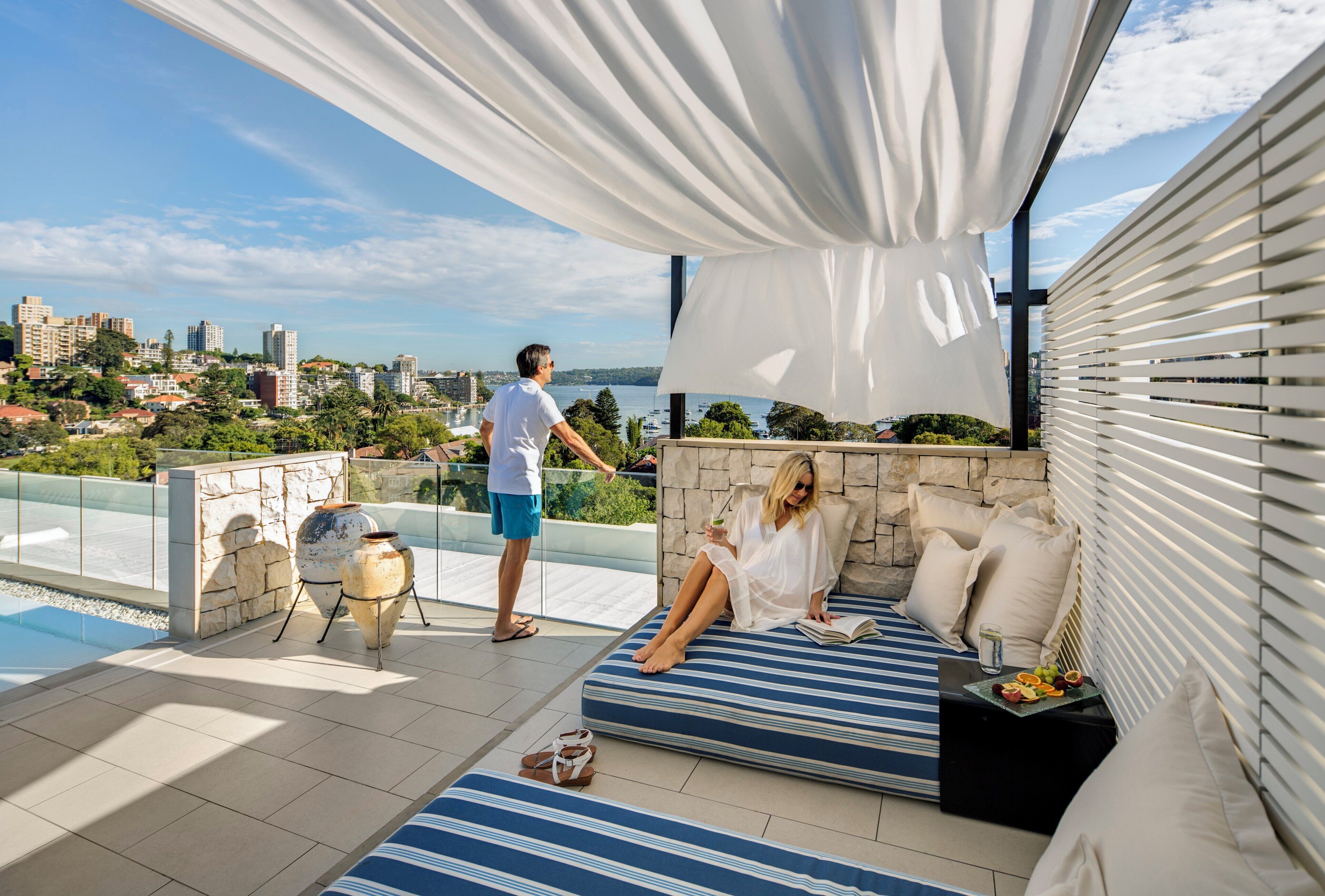 Une terrasse sur le toit offrant une vue sur la ville, un coin salon avec des coussins et une table garnie de fruits.