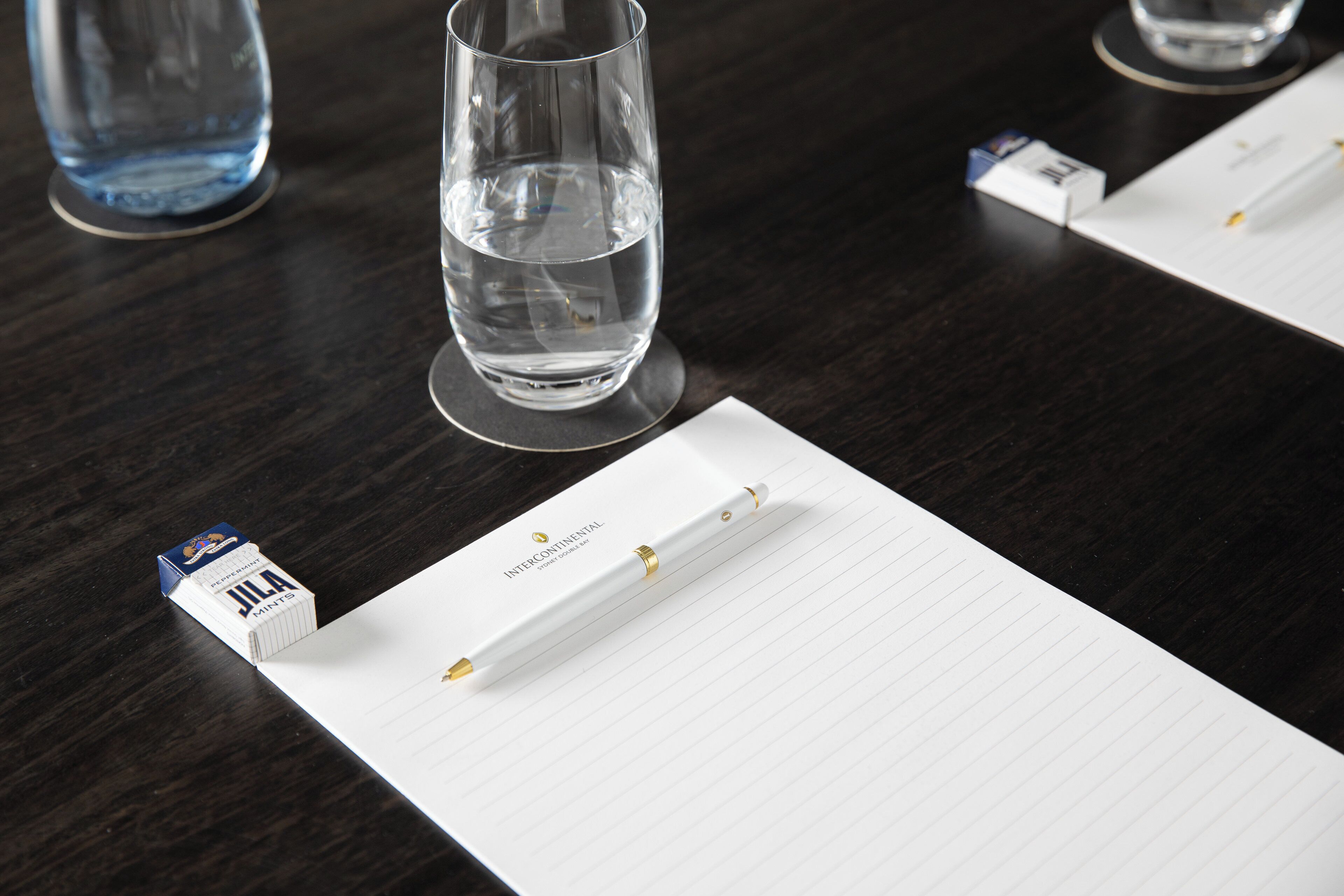 Una mesa con un cuaderno, un bolígrafo y una cajita de caramelos mentolados J&J.