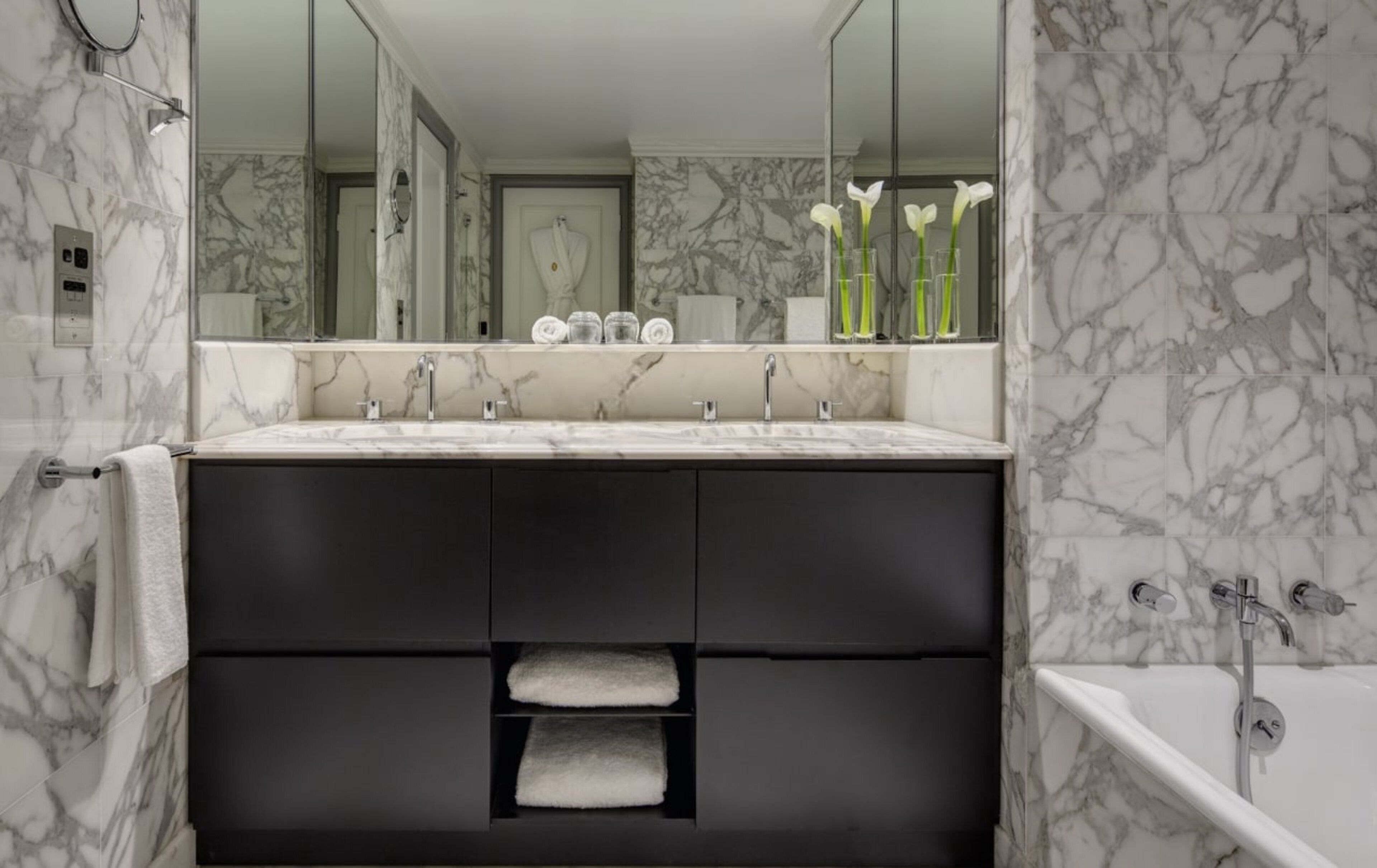 Un bagno moderno con un mobile lavabo in marmo, uno specchio grande e una vasca da bagno.
