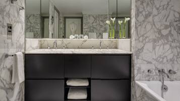 Un bagno moderno con un mobile lavabo in marmo, uno specchio grande e una vasca da bagno.