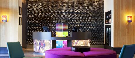 A reception area with a modern design, featuring a reception desk, a colorful wall, and seating arrangements.