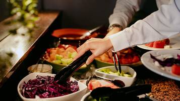 A person serving food from a buffet with various dishes visible.