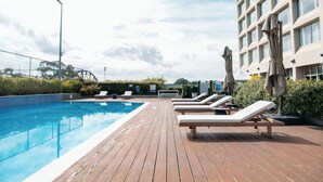 A rooftop pool area with wooden deck, lounge chairs, and umbrellas. - Mercure Sydney Parramatta (Rosehill)
