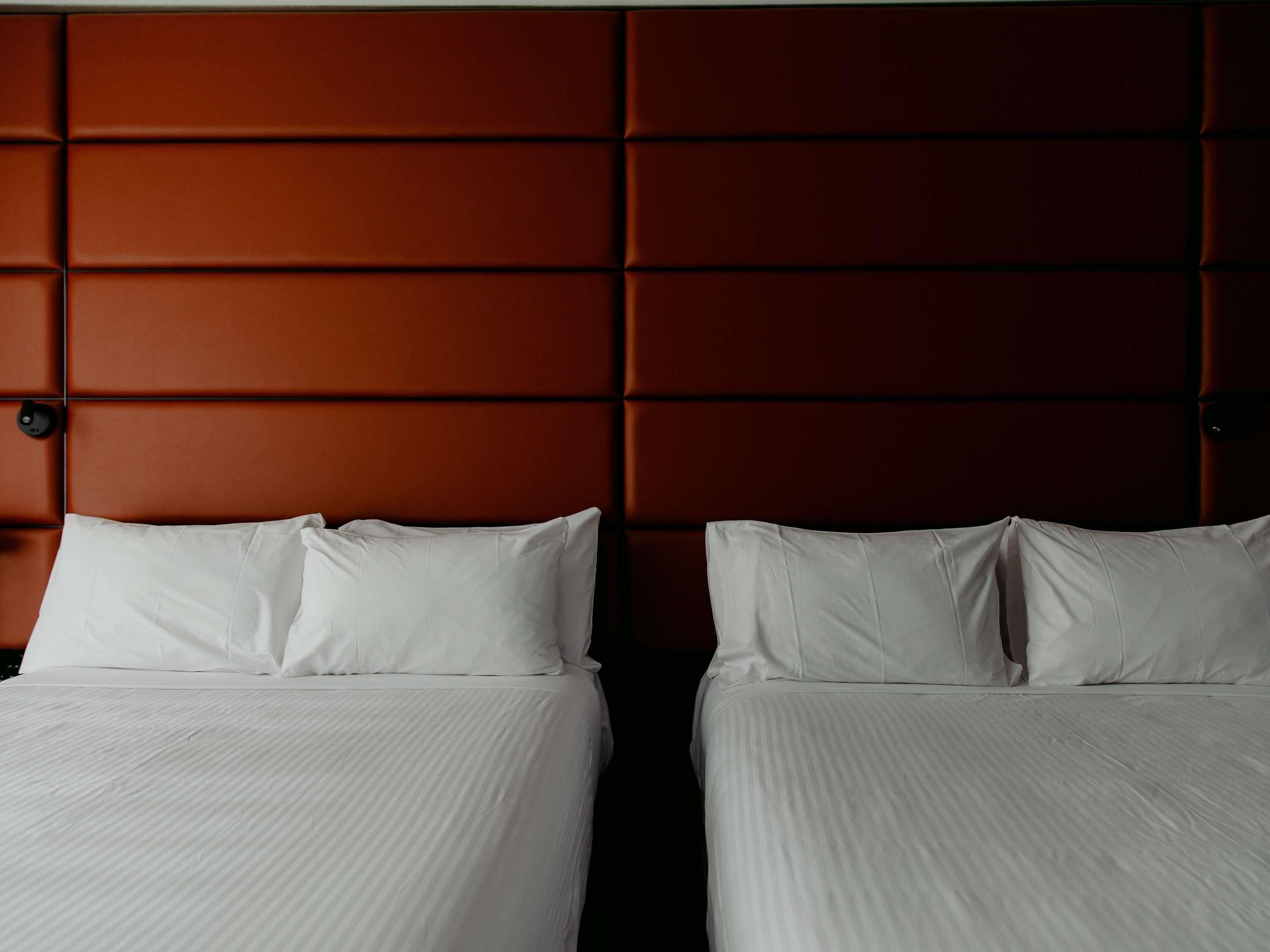 Une chambre d’hôtel avec deux lits, chacun étant équipé de draps et d’oreillers blancs.