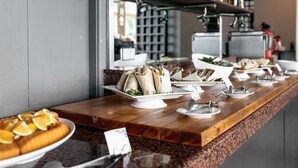 A buffet setup with various food items and a coffee machine in the background. - Mercure Sydney Parramatta (Rosehill)
