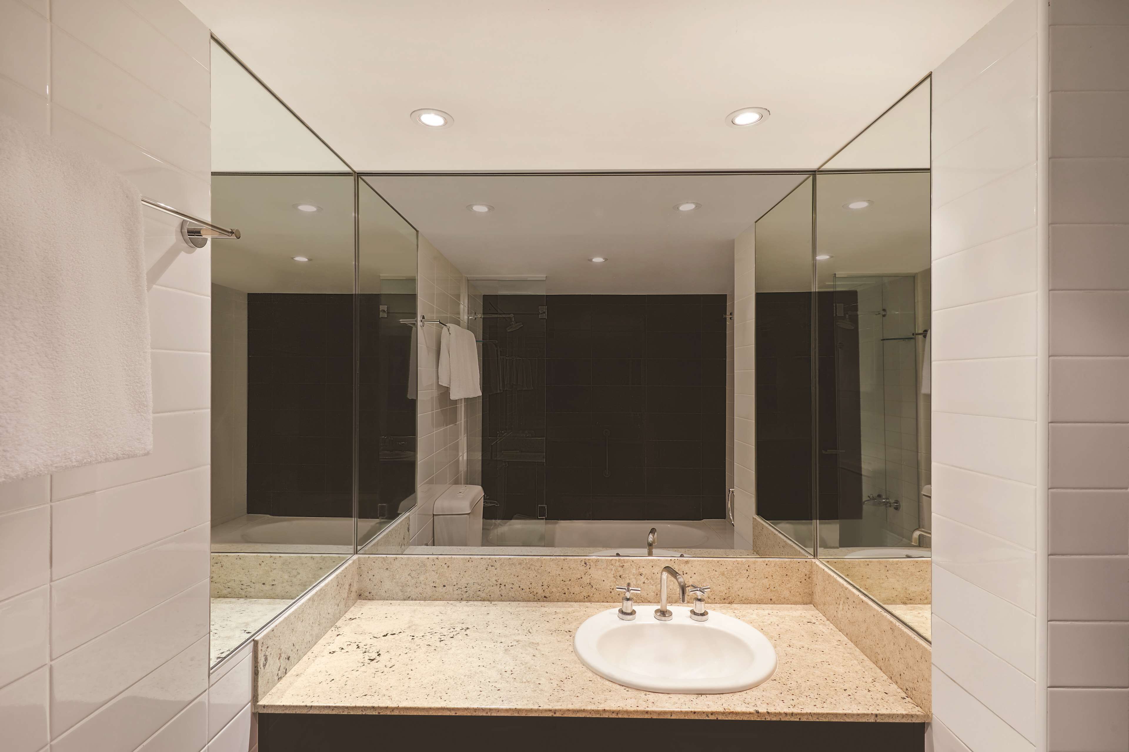 A modern bathroom with a large mirror, a sink, and a glass-enclosed shower area.