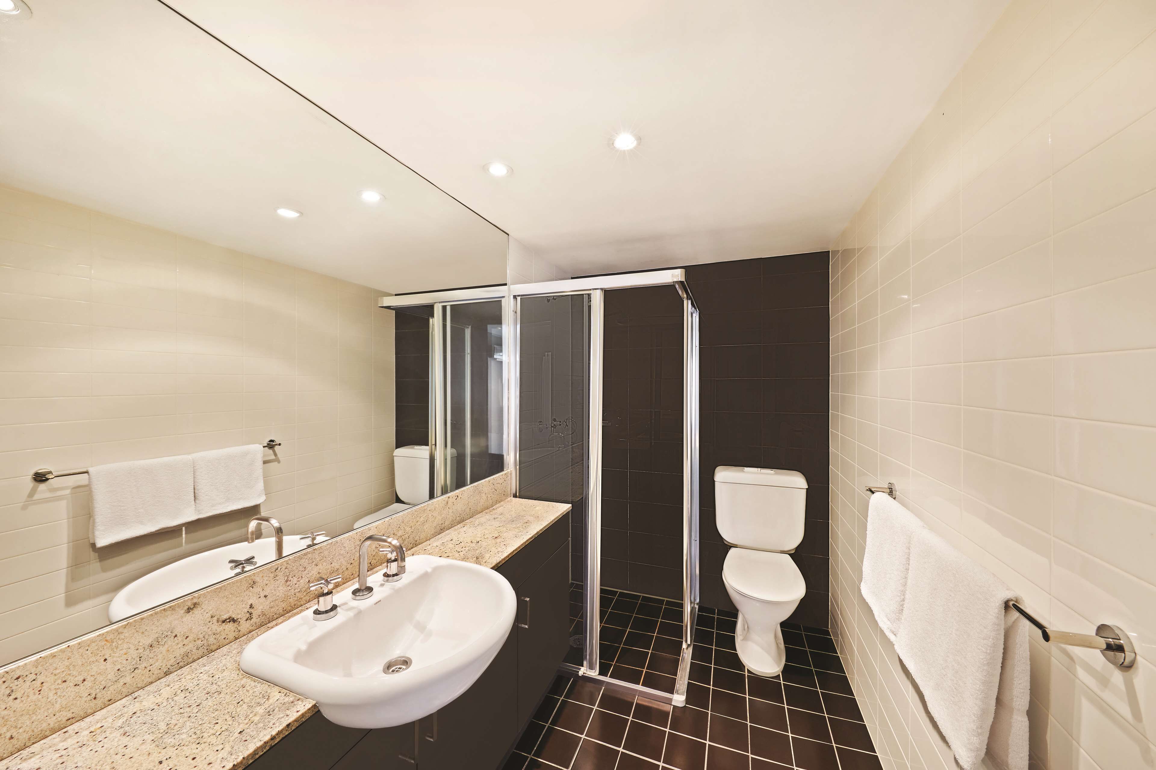 Un baño moderno con lavamanos, espejo y retrete.