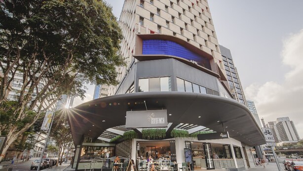 A modern building with a curved entrance, a sign for 'APIL', and a 'LANE' sign indicating a bike lane. - Mercure Brisbane King George Square (Brisbane)
