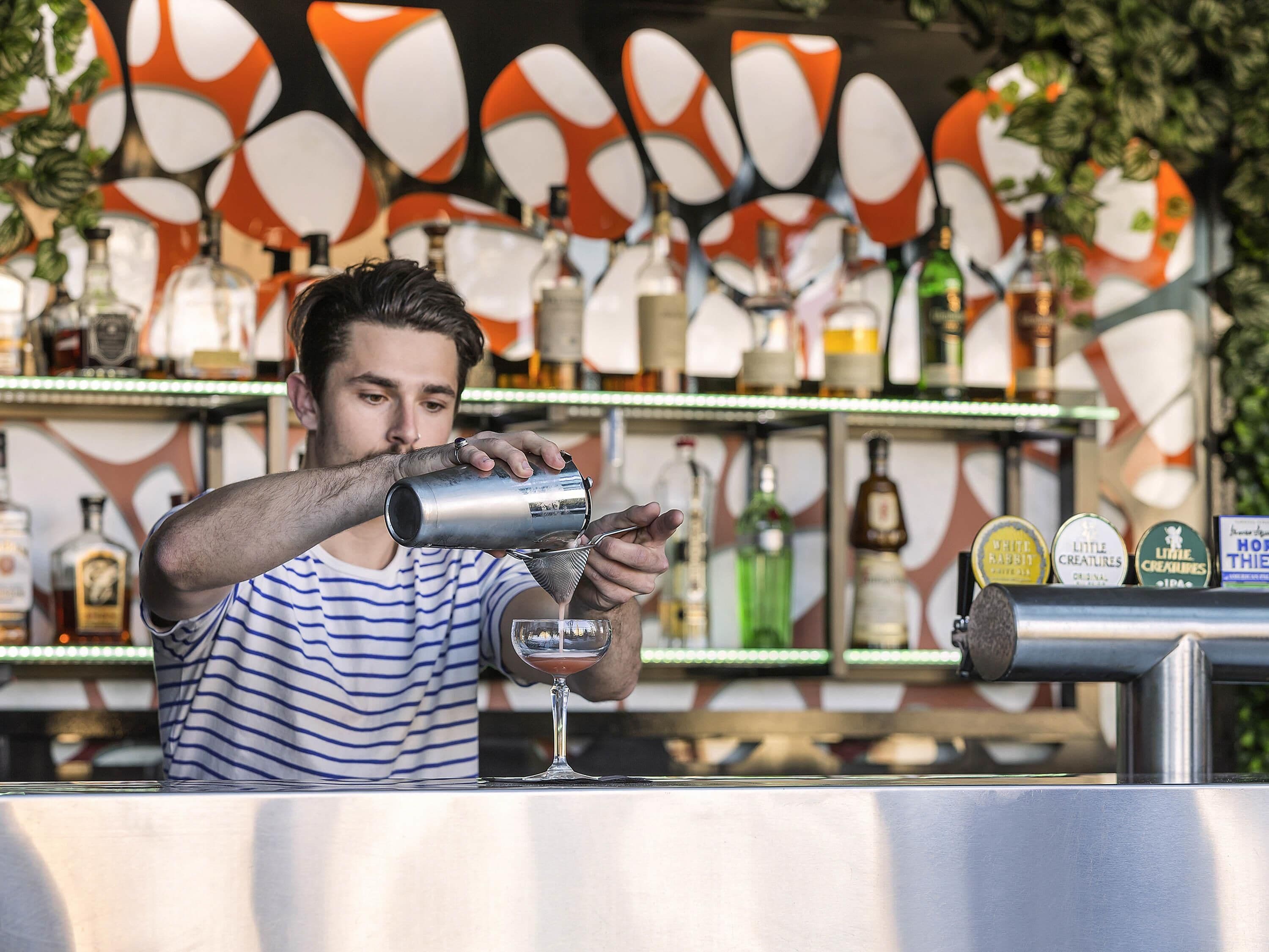 A bartender pouring a drink into a glass.