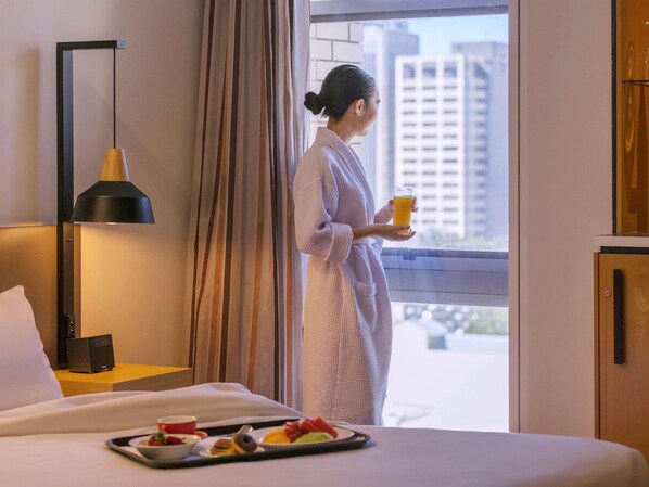 Enjoy a comfortable stay in this stylish room with a large bed, bedside table, and window with curtains.