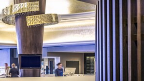 A lobby with a large, circular reception desk, a decorative metal sculpture, and a television screen. - Mercure Brisbane King George Square (Brisbane)