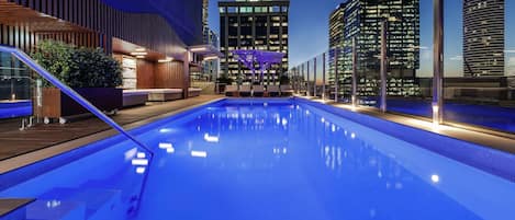Una piscina al aire libre, sillones reclinables de piscina