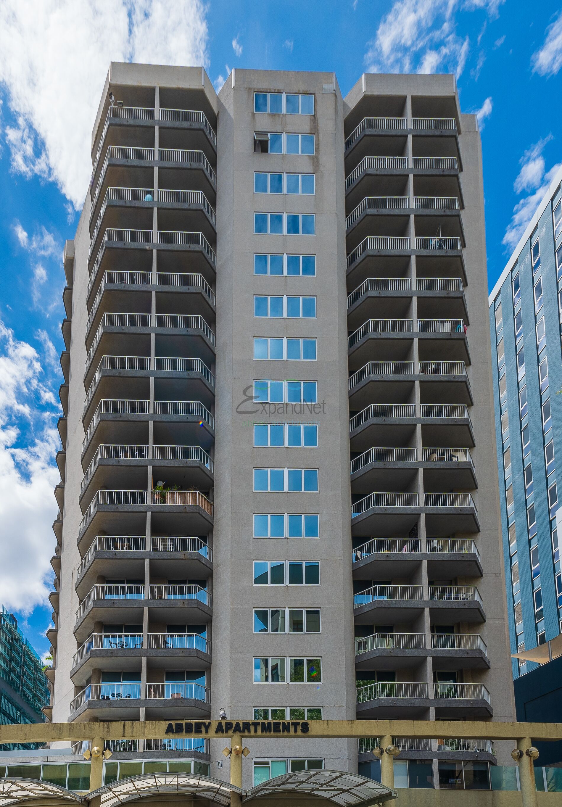 A high-rise building with multiple balconies and a clear sky.